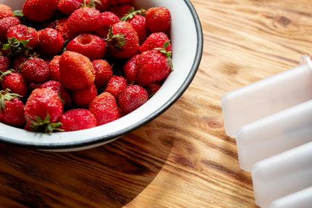 strawberry harvest in an iron bowl on a wooden background, for making homemade ice cream, top viewの写真素材