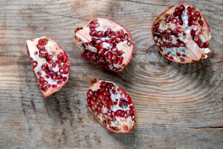 pomegranate divided into 4 pieces, on a wooden background, top viewの写真素材