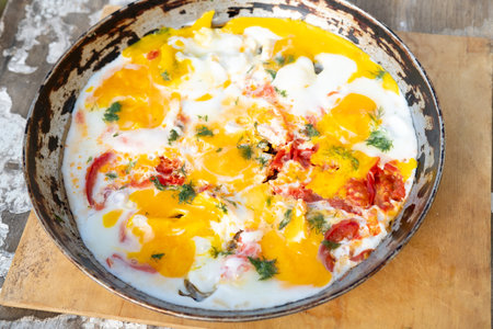 scrambled eggs cooked in a frying pan with tomatoes and herbs, outsideの写真素材