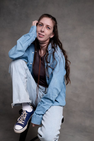 beautiful and long-haired woman in stylish clothes posing in a photo studio and smiling. a model...
