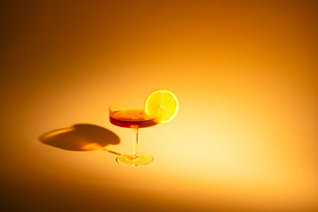 glass of drink with a slice of orange on an orange background, with hard lightの写真素材