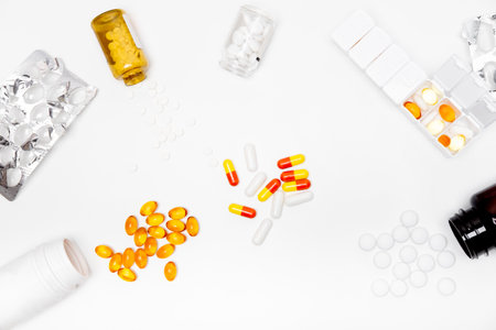pillbox by days of the week with fish oil and various pills, capsules and jars scattered on a white background, top viewの写真素材