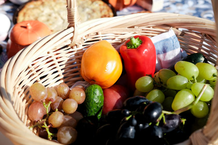 picnic basket with different types of grapes, red pepper, tomatoes and cucumber, close-up outdoors