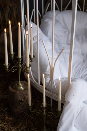 long white candles on the floor next to bed linensの写真素材