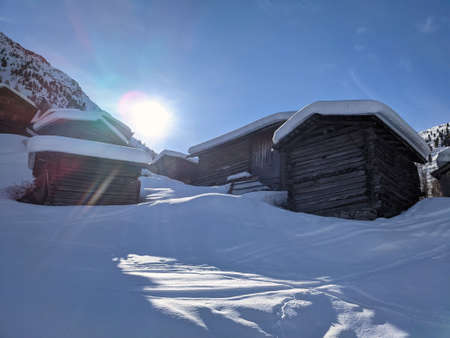a small hamlet in winter above the small village of monstein in davos. Sunny winter morning landscape with mountains.の写真素材