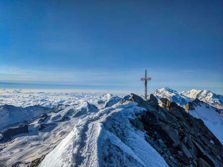 Dom 4545m . Highest mountain in Switzerland. Summit cross, valais alps. mountaineering, rock climbing. blue sunny skyの写真素材