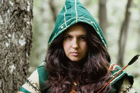 Staging photo of beautiful woman in fantasy suit with hood in forestの写真素材