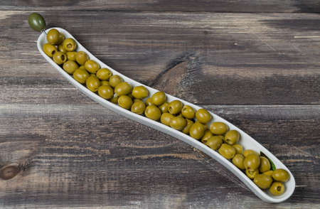 Green olives in vase on wood tableの写真素材