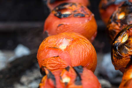 Grilled tomatoes on skewers close up with fire and juiceの写真素材