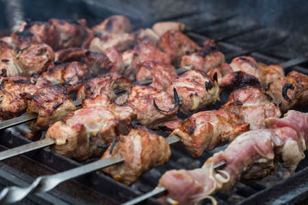 Juicy slices of meat on skewers in smoke outdoorsの写真素材