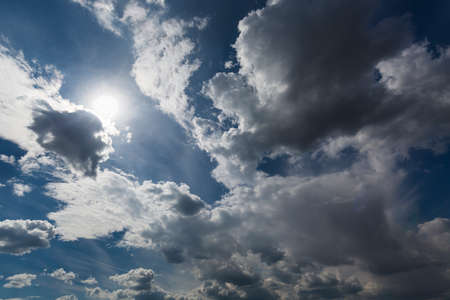 Dark blue sky, white clouds and sun.