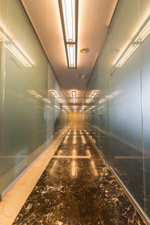 Modern office corridor with glass doors and reflectionsの写真素材