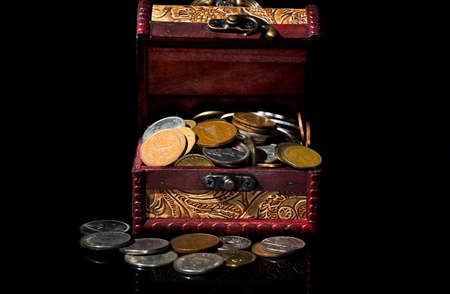 old coins in chest on black background with reflections