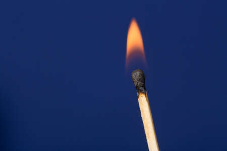 Burning match stick against dark blue backgroundの写真素材