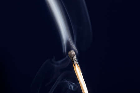 Extinguished match close up with smoke on dark blue backgroundの写真素材