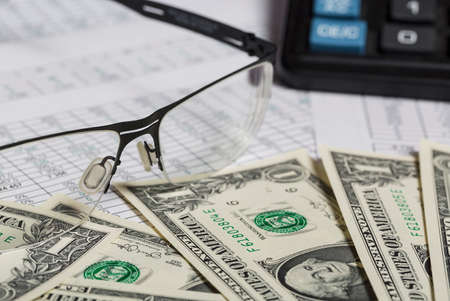 Business research. Closeup of spectacles, dollar bills, calculator on paper with digits.の写真素材