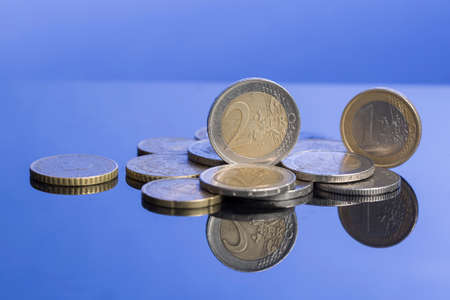 stack of coins of Europe on nice blue background with reflection.