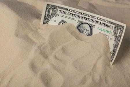 Finance concept. One dollar bank note in the sand.の写真素材