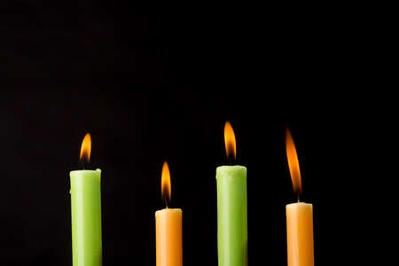 Four burning colorful candles on black background.の写真素材