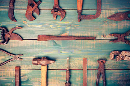 different rusty construction instruments on the green wooden background.の写真素材