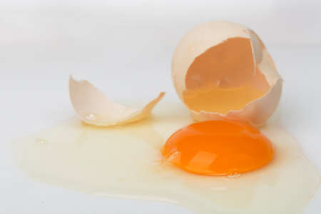 Broken brown egg on a white background.の写真素材