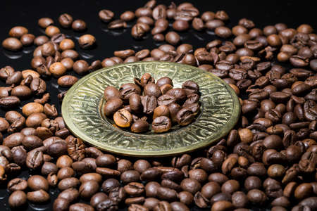 Coffee beans in gold plate on black background.の写真素材
