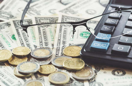Closeup of glasses on dollar banknotes with coins and calculator. Business concept.
