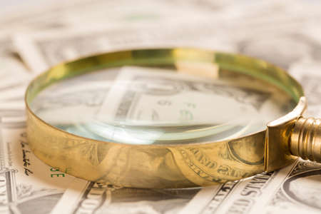 Finance concept. Gold magnifying glass on dollar banknotes. Selective focus.の写真素材