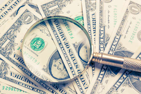 Finance concept. Gold magnifying glass on dollar banknotes.の写真素材