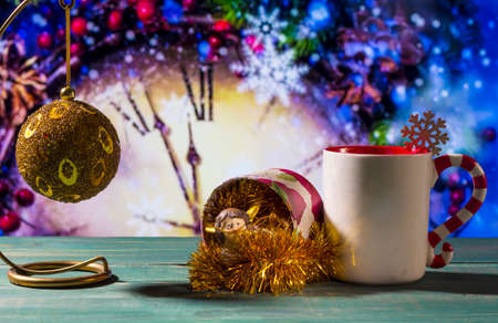 Christmas theme with toy ball, angel and mug on green wooden surface against nice clock background.の写真素材