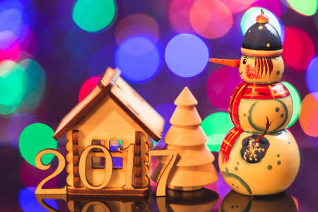 New Year theme. 2017 year figures with decorative house, fir tree and snowman on lights background.の写真素材