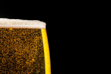 glass of beer with bubbles on black background with free space for textの写真素材