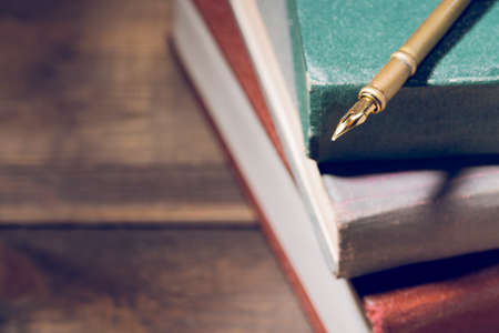 Closeup of fountain pen on stack of old books.の写真素材