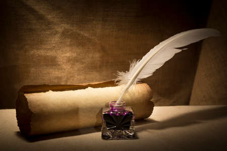 Literature concept. Old inkstand with feather near scroll on canvas background.
