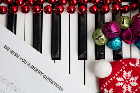 Christmas music concept. Printed music on the pianto with jingle bells, red christmas balls and hat.の写真素材
