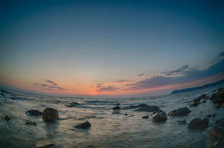 Sunset over the coast with stones of Black Sea, Russia. Fish-eye lens.の写真素材