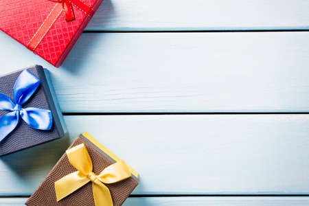 Colorful gift boxes on nice blue wooden background with free space.