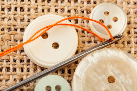 Sewing concept. Needle with thread and snaps close up on burlap background.の写真素材