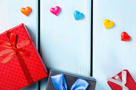 Colorful gift boxes with decorative hearts on nice blue wooden background with free space.の写真素材