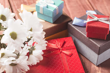 White chrysanthemum flowers with gift boxes on wooden table. Holiday card.