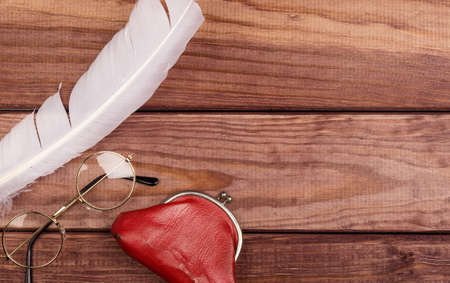 Old glasses near feather and vintage purse on wooden background with copy spaceの写真素材