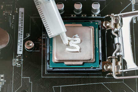 Applying thermal paste during CPU installation close up in the motherboardの写真素材