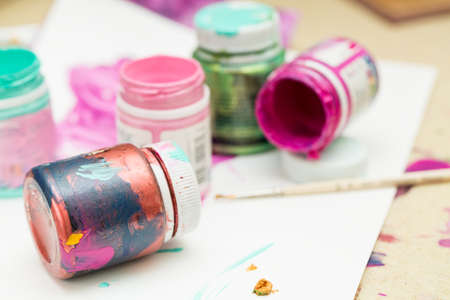 Different colorful paints and brush on white paper. Selective focus.の写真素材