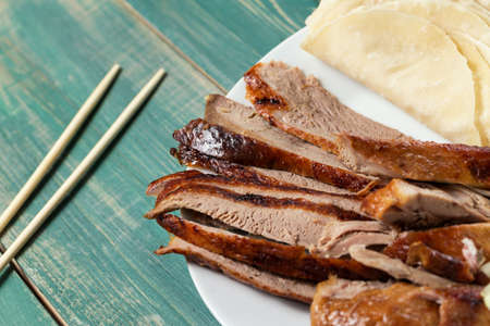 Peking Duck - Chinese roast duck pancakes on wooden green table with chopsticks close up.の写真素材