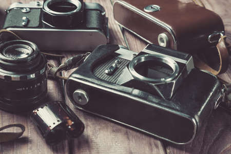 Old film cameras with lens and case on wooden background. Vintage toned and selective focus.の写真素材