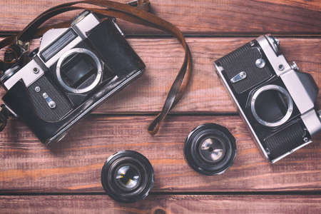 Old film cameras with lenses and strap on wooden background. Vintage toned and top view.の写真素材