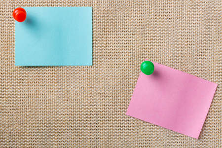 Blue and pink sticker notes with push pins on canvas background.の写真素材