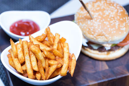 French fries on white plate with ketchup and burger. Focus on fries.の写真素材