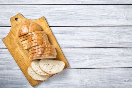Fresh bread slices on cutting board against white grey wooden background. Top view.の写真素材