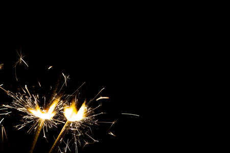 Three bright festive Christmas sparklers on black background with free spaceの写真素材